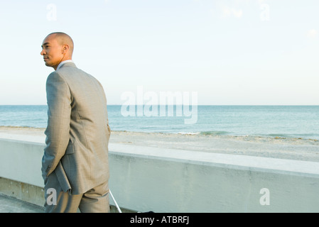 Imprenditore passeggiate in riva al mare che guarda lontano Foto Stock
