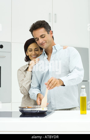 Accoppiare la cucina insieme in cucina, donna pendente sulla testa di uomo di spalla, sia guardando verso il basso Foto Stock