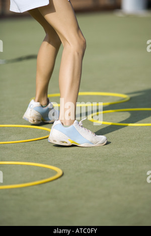 Ragazza adolescente in scarpe da tennis in piedi accanto a cerchi in materiale plastico a basso angolo di visione, ritagliato Foto Stock