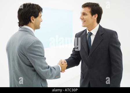 Due imprenditori stringono le mani, sorridente ad ogni altro, vista laterale Foto Stock