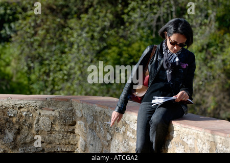 Appoggio turistico e fumare durante la lettura del suo libro guida, Ronda, Andalusia, Spagna. Foto Stock