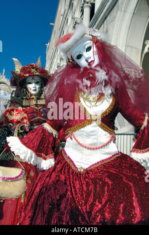 Due femmina masqueraders indossando maschere veneziane e costume rosso nel carnevale di Venezia 2005 Foto Stock