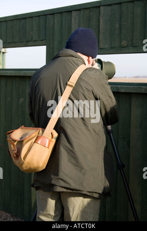 Osservazione degli uccelli costieri, vestito di verde, con portata da nascondere a Sandside, Marshside RSPB Riserva, Southport, Merseyside, Regno Unito Foto Stock