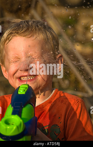 Boy squirting viso con acqua Foto Stock