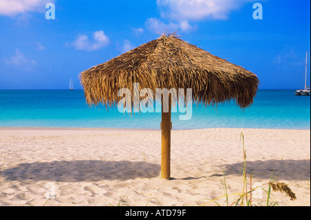 Con tetto di paglia di un ombrellone si siede nella sabbia sull'isola caraibica di Turks & Caicos Foto Stock