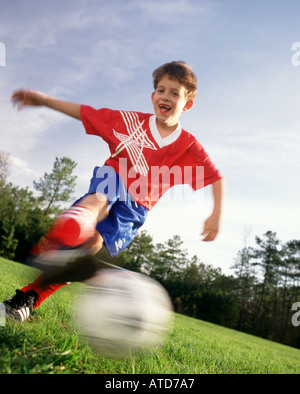 Bassa angolazione di 10 anno vecchio ragazzo calci ad un pallone da calcio durante un gioco Foto Stock