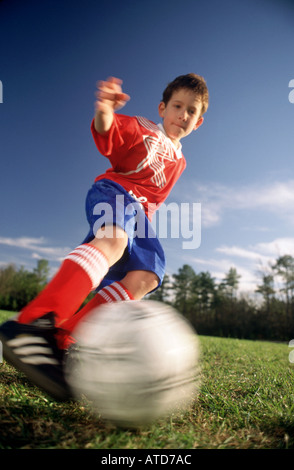 Bassa angolazione di 10 anno vecchio ragazzo calci ad un pallone da calcio durante un gioco Foto Stock