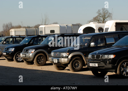 Una fila di 4x4 a quattro a quattro veicoli allineate in una fila di traino scatole di cavallo in corrispondenza di un evento equestre in un grande maneggio cantiere Foto Stock