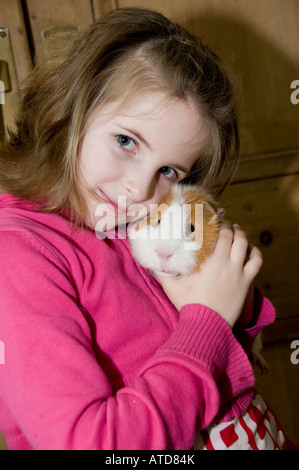 Giovane ragazza di nove anni tenendo il suo animale domestico hamster nelle sue braccia cercando carino a casa Foto Stock