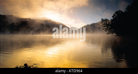 La nebbia e la nebbia si elevano al di sopra dei Bear Rock Lake in Blue Ridge Mountains del North Carolina con il sole che sorge Foto Stock