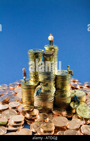 Costruzione di lavoratore figure su cumuli di denaro e denaro pile Foto Stock