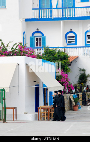 Due greci sacerdoti ortodossi a piedi di fronte all' Hotel Calypso, Lipsi, isole Dodecanesi, Grecia Foto Stock