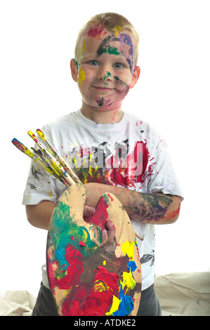 6 anno vecchio ragazzo sta poudly con il pittore della tavolozza e pennelli. Foto Stock