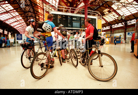 Quattro maschi i ciclisti dopo la Londra a Brighton in bicicletta in attesa alla stazione ferroviaria di Brighton per un treno home Foto Stock