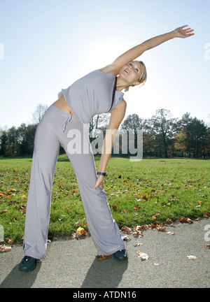Giovane donna facendo esercizi di stretching nel parco Foto Stock