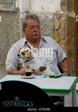 Un uomo seduto al tavolino di un bar a bere caffè con un cane sul suo giro di Almeria in Spagna. Foto Stock