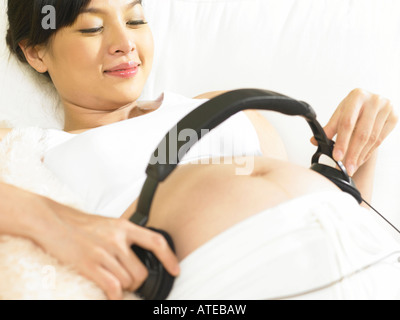 Donna incinta con le cuffie Foto Stock