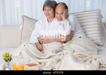 Coppia matura che abbraccia ogni altro sul letto Foto Stock