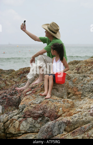 Uomo maturo e la sua nipote seduto su una roccia e scattare una foto di se stessi Foto Stock