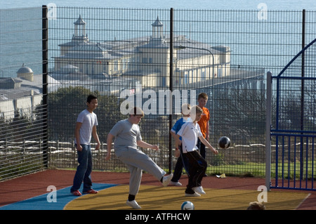 Hastings Pier con ragazzi che giocano a calcio in primo piano in Hastings East Sussex Regno Unito Foto Stock