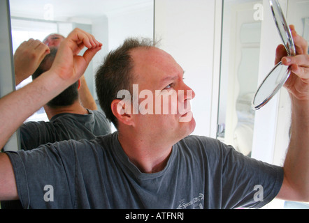 L'uomo controllando il suo assottigliamento dei capelli Foto Stock