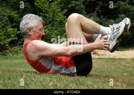 Un uomo anziano è stretching dopo una lunga corsa Foto Stock