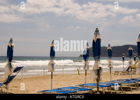 Una spiaggia con alcune vuote di sedie a sdraio e ombrelloni chiusi in Liguria, Italia Foto Stock
