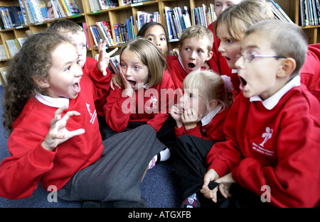 Avviso luminoso ragazzi e ragazze in una scuola primaria storytelling classe Foto Stock