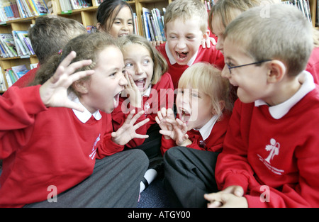 Avviso luminoso ragazzi e ragazze in una scuola primaria storytelling classe Foto Stock