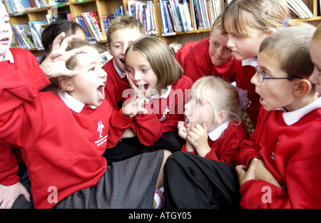 Avviso luminoso i ragazzi e le ragazze di interagire con glee in una scuola primaria storytelling classe Foto Stock