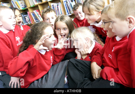 Avviso luminoso ragazzi e ragazze in una scuola primaria storytelling classe Foto Stock