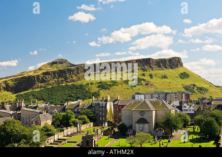 Salisbury Crags e Arthur' Seat salire dietro Canongate Kirk all'estremità orientale del Royal Mile nel centro storico di Edimburgo, Regno Unito Foto Stock