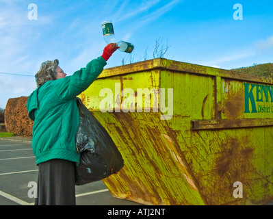 Donna gettare i rifiuti di imballaggio di plastica in un locale competente dedicato saltare per il riciclaggio Foto Stock