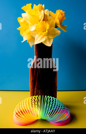 Arty, creativa e contemporanea composizione a molla con narcisi e slinky molla Foto Stock