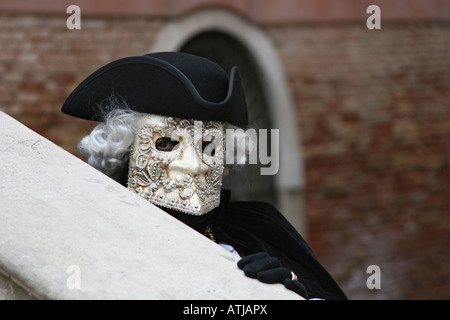 Ritratto di un uomo vestito in costume e maschera guardando sopra la ringhiera di una scala di pietra il Carnevale di Venezia Vento Italia Foto Stock