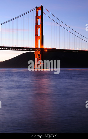 Torre meridionale del Golden Gate Bridge si illumina contro uno sfondo di illuminata delicatamente le nuvole al tramonto il colpo da Fort Point area Foto Stock