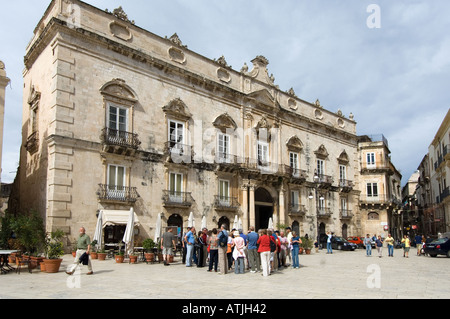 Un gruppo di turisti ascoltare una guida nella Piazza del Duomo di Siracusa, in Sicilia di fronte a palazzo Ortigia Foto Stock