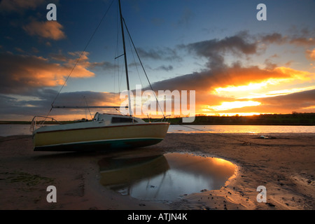 Barca in appoggio su un sandbank a bassa marea in Alnmouth estruary l'ansa tramonto si riflette in una piscina di acqua Foto Stock
