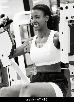 Donna che utilizza macchina ginnica in palestra B W Foto Stock