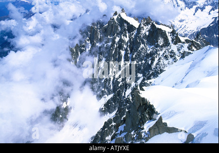 Le Aiguilles a nord-ovest della Aiguille du Midi che appare attraverso le nuvole, le Alpi francesi Foto Stock