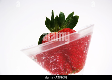 Fragola rossa in un bicchiere di acqua Rote Erdbeere in einem Glas mit Wasserblasen frisch Foto Stock