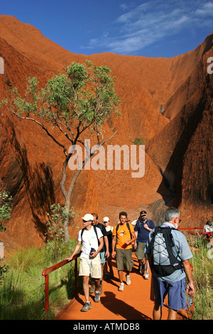 La folla di turisti a piedi intorno alla base del famoso Ayers rock Uluru sul percorso circolare di Territorio del Nord Australia Foto Stock