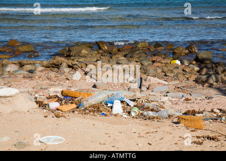 Flotham e Jetsam spazzano sulla spiaggia sporca con borse di plastica e lattine di stagno nel resort. Egitto Asia Foto Stock