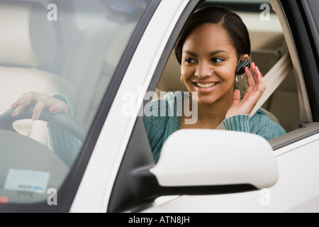 Donna africana utilizzando dispositivo vivavoce in auto Foto Stock