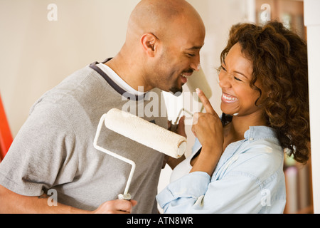 African coppia essendo sciocco con rulli di vernice Foto Stock