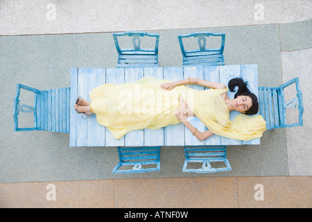 Angolo di alta vista di una giovane donna sdraiata su un tavolo Foto Stock