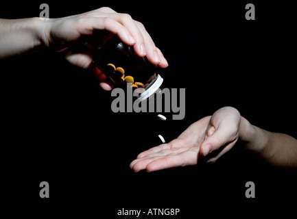 Una donna versando due compresse da una bottiglia di pillole Foto Stock