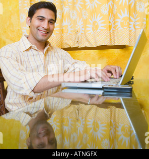 Ritratto di un giovane uomo che utilizza un computer portatile e sorridente Foto Stock