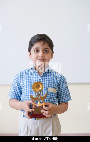 Ritratto di uno scolaro tenendo un trofeo e sorridente Foto Stock