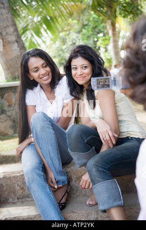 Vista posteriore di un uomo le riprese di due giovani donne con un home video camera Foto Stock